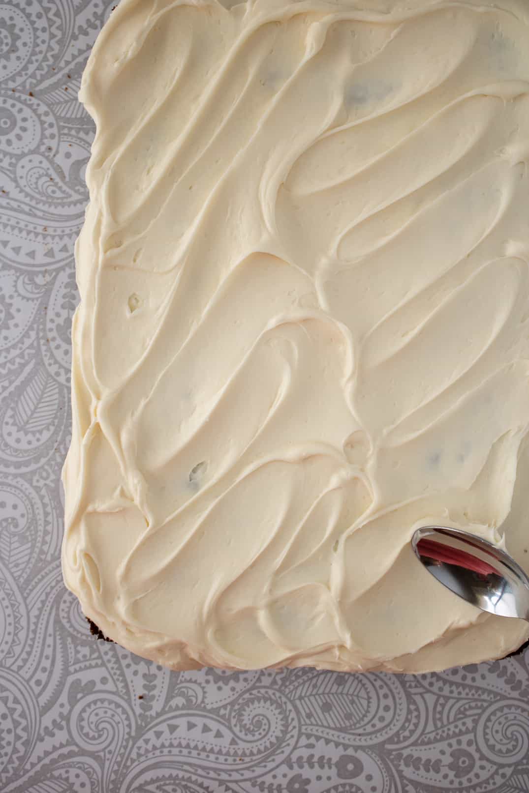 Spreading frosting on carrot cake with the back of spoon