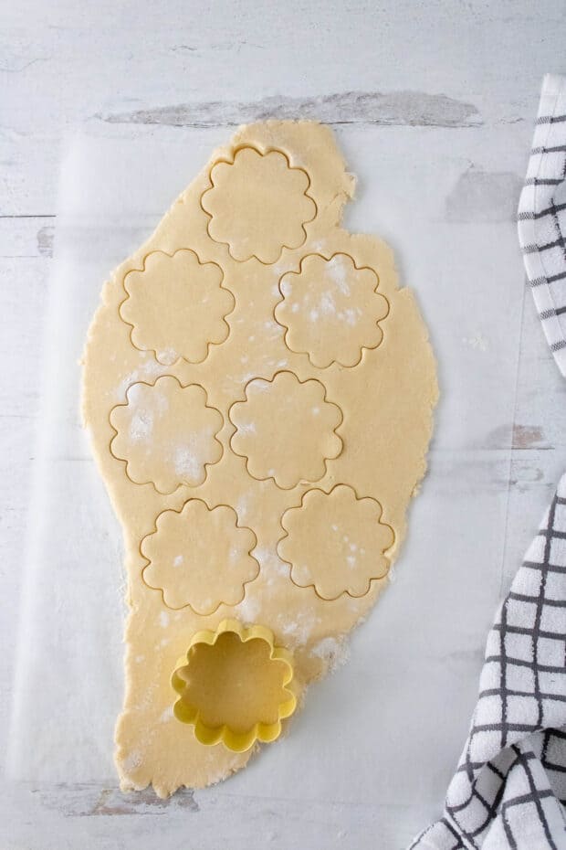 Rolled out cookie dough for Southern tea cookies being cut with a flower-shaped cookie cutter 