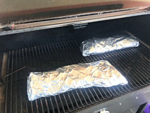 Baby back ribs wrapped in foil and placed in smoker