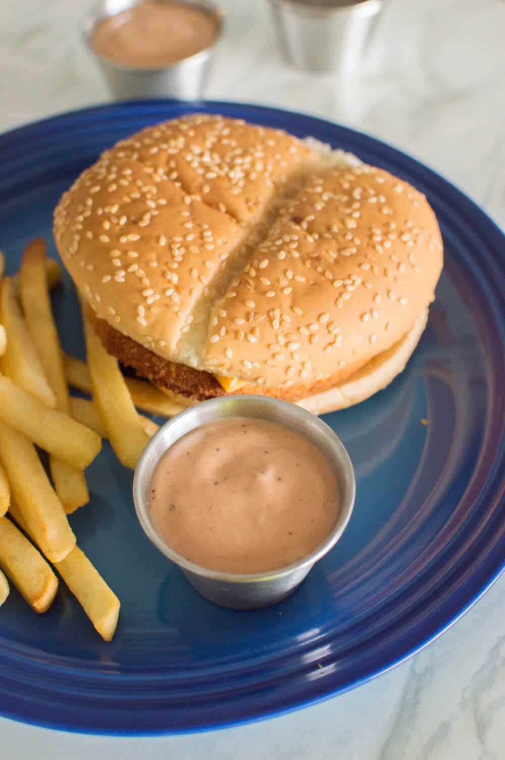 Homemade Guthrie’s Sauce in a small, silver bowl with a chicken burger and French fries
