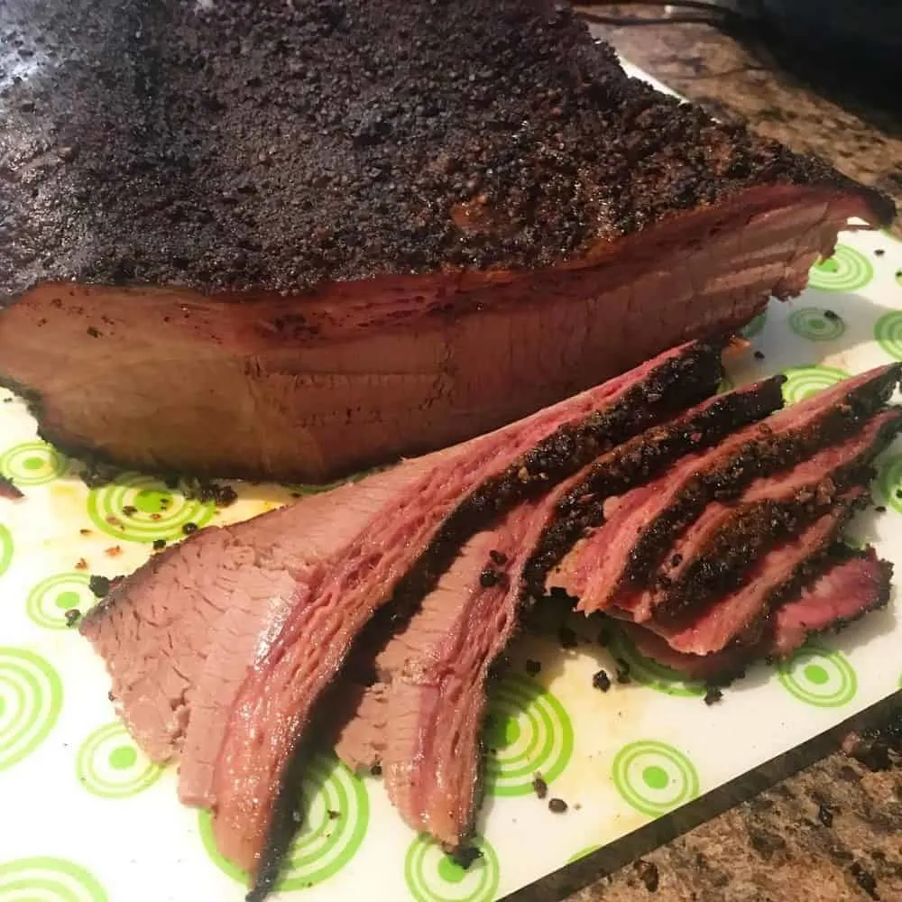 sliced beef brisket on a white and green cutting board