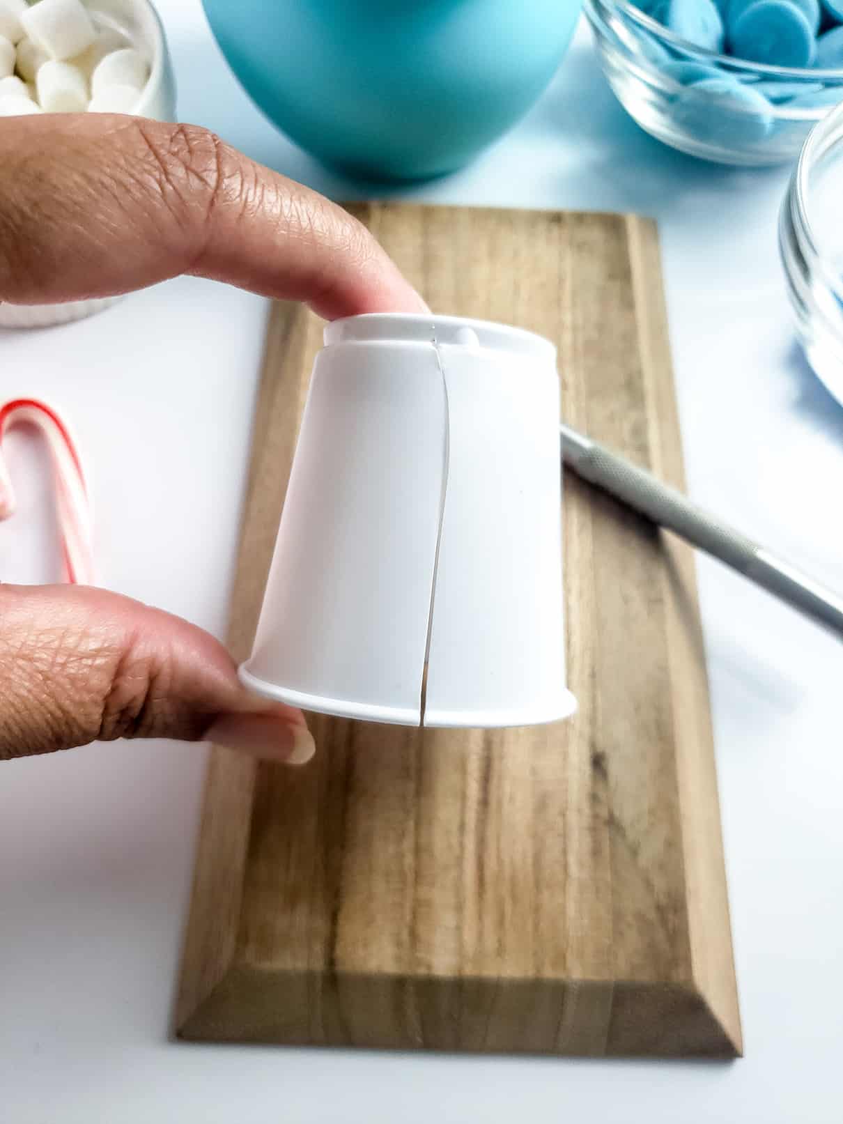 Cutting a slit in a disposable cup to make Winter Wonderland Hot Cocoa Bombs
