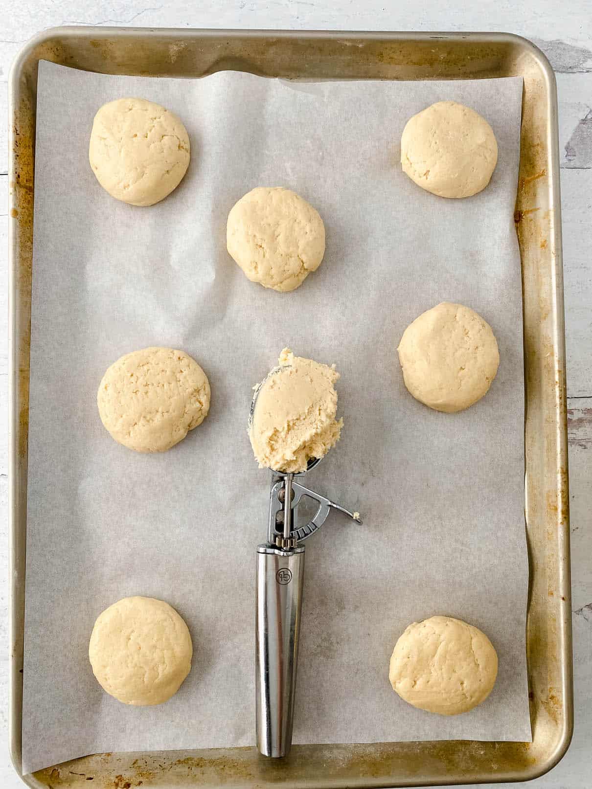 Scooping out cookie batter onto a parchment-lined baking sheet