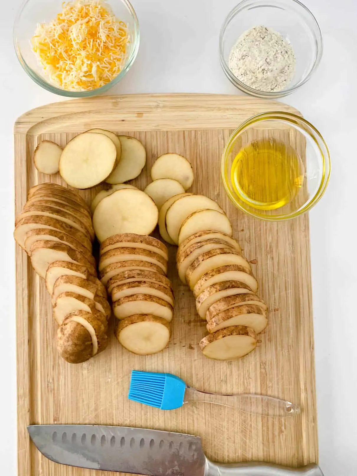 Cutting russet potatoes in thin slices, on a wooden cutting board