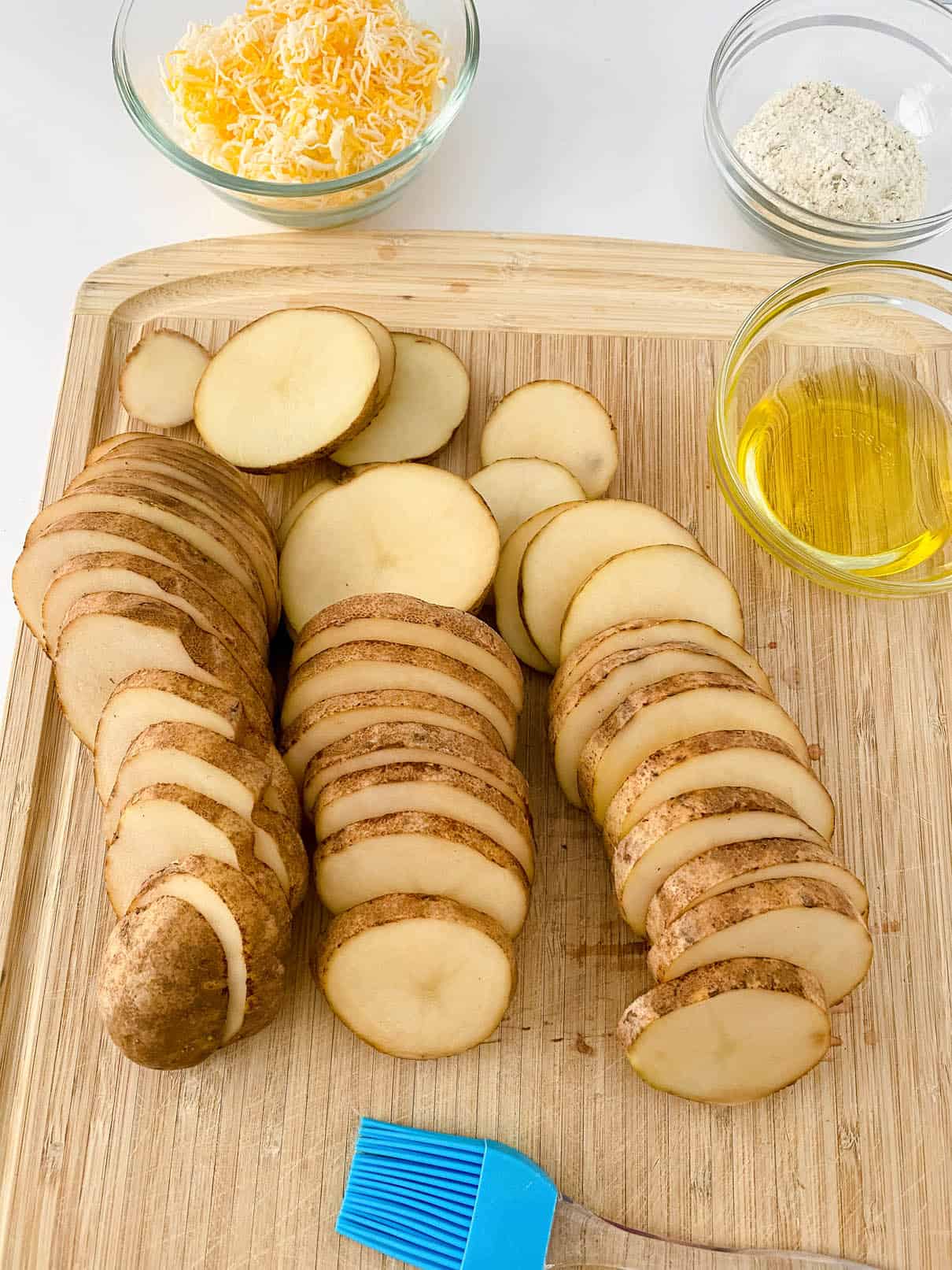 Cutting russet potatoes in thin slices, on a wooden cutting board