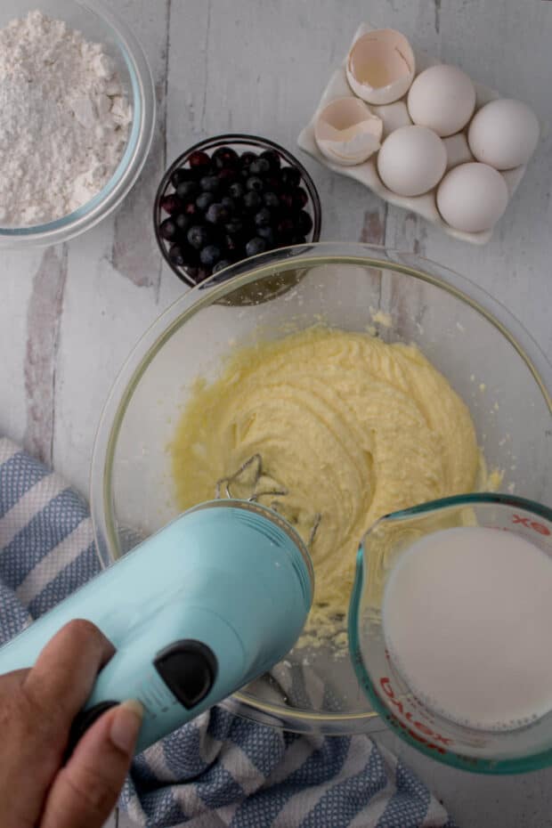 Adding milk to a bowl of wet ingredients to make blueberry muffins