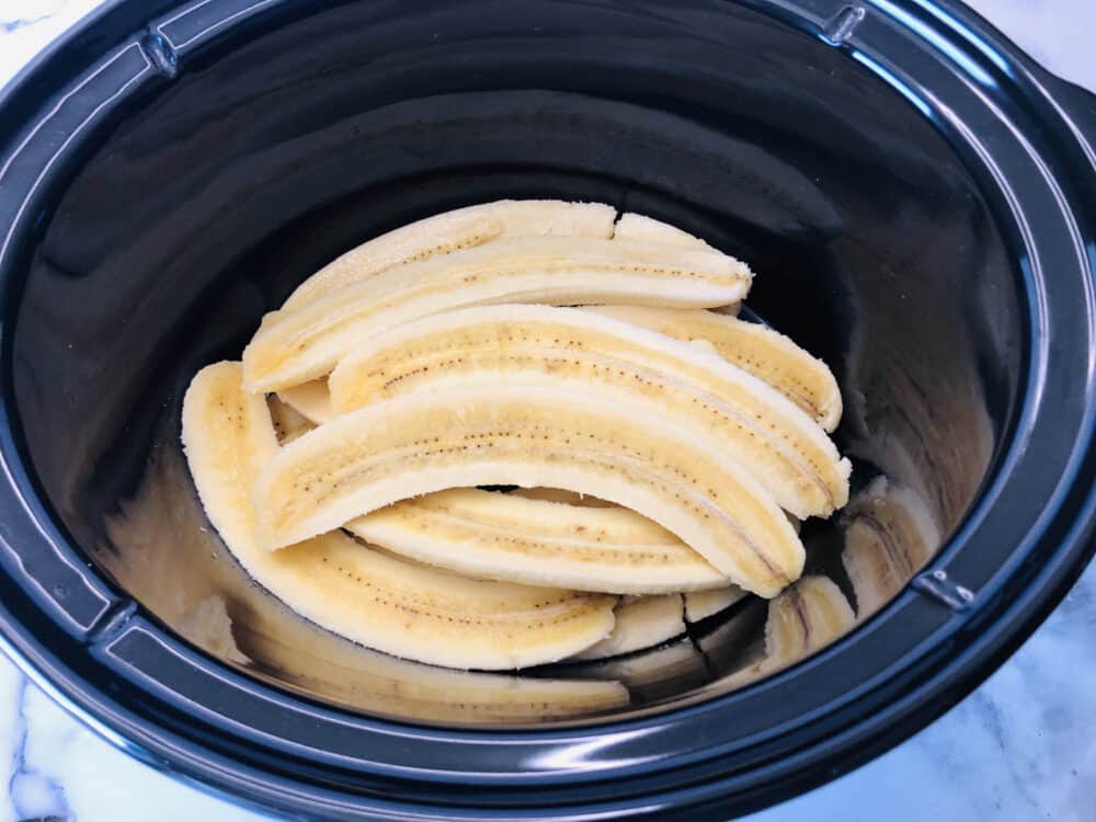 Placing halved bananas in a slow cooker