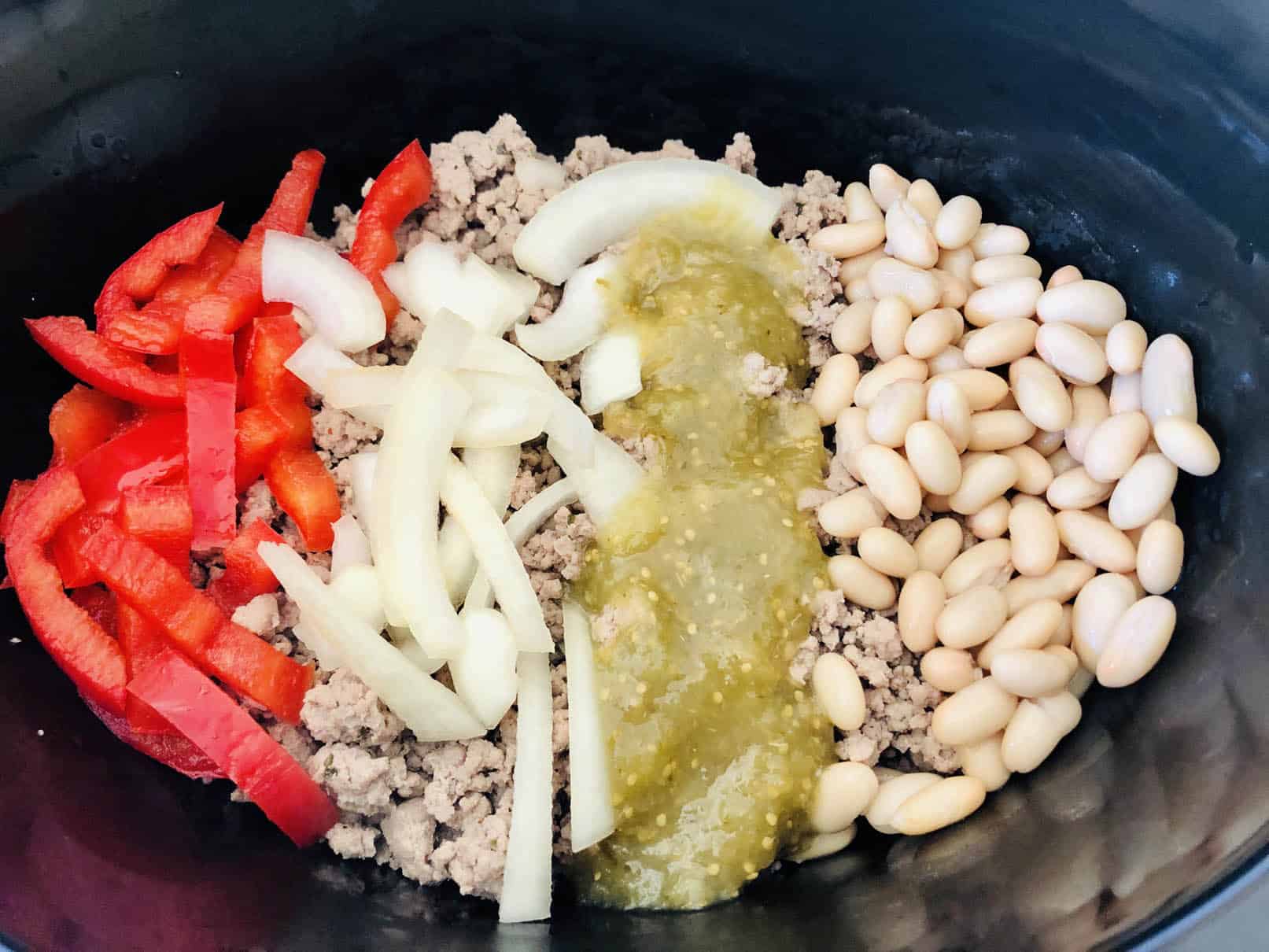 Adding ingredients to slow cooker tacos in a slow cooker