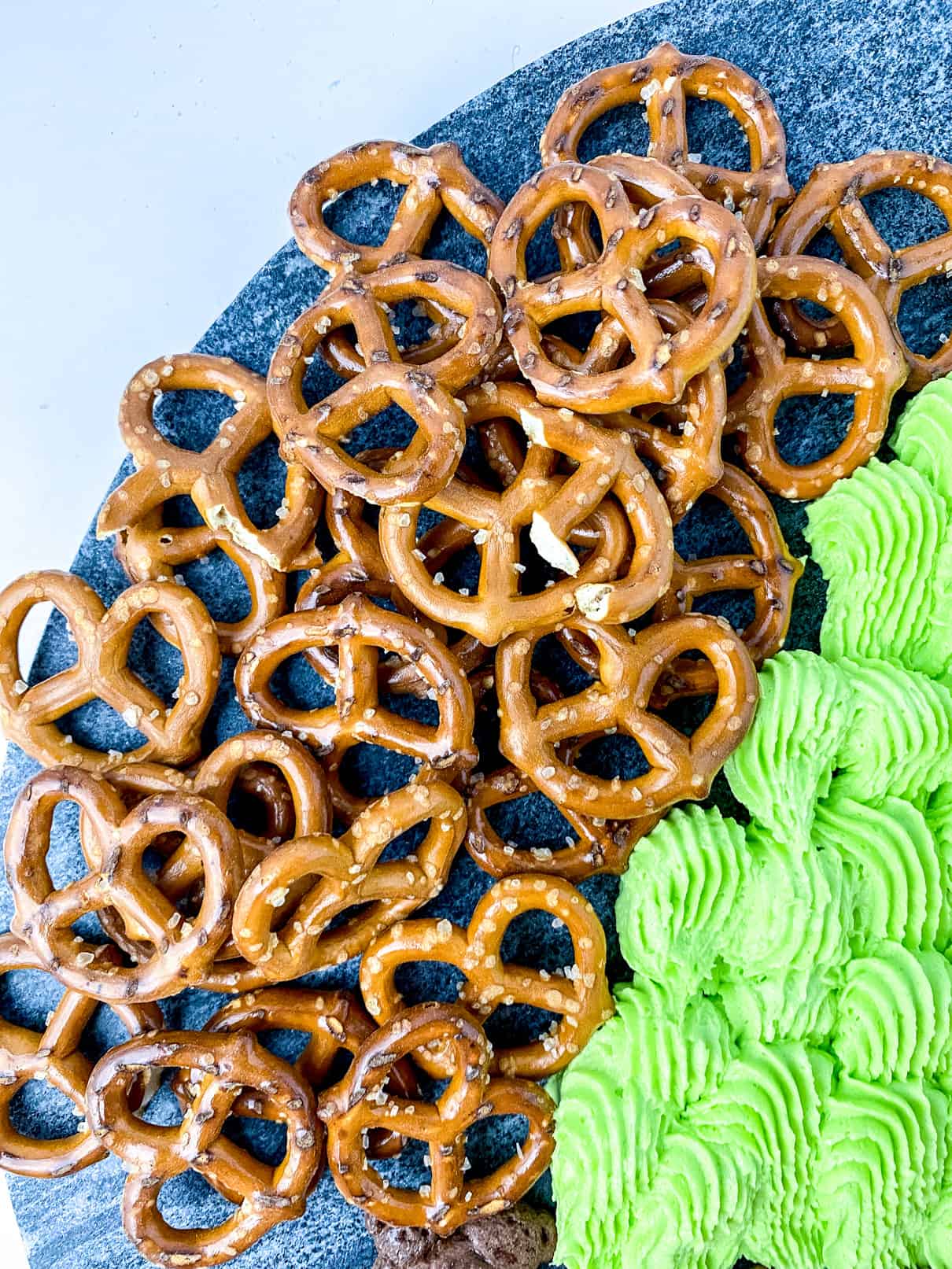 Bird’s eye view of hard pretzels, next to green icing
