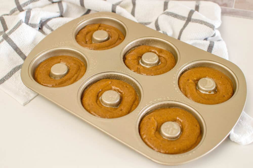 Adding gingerbread donut batter into a donut pan