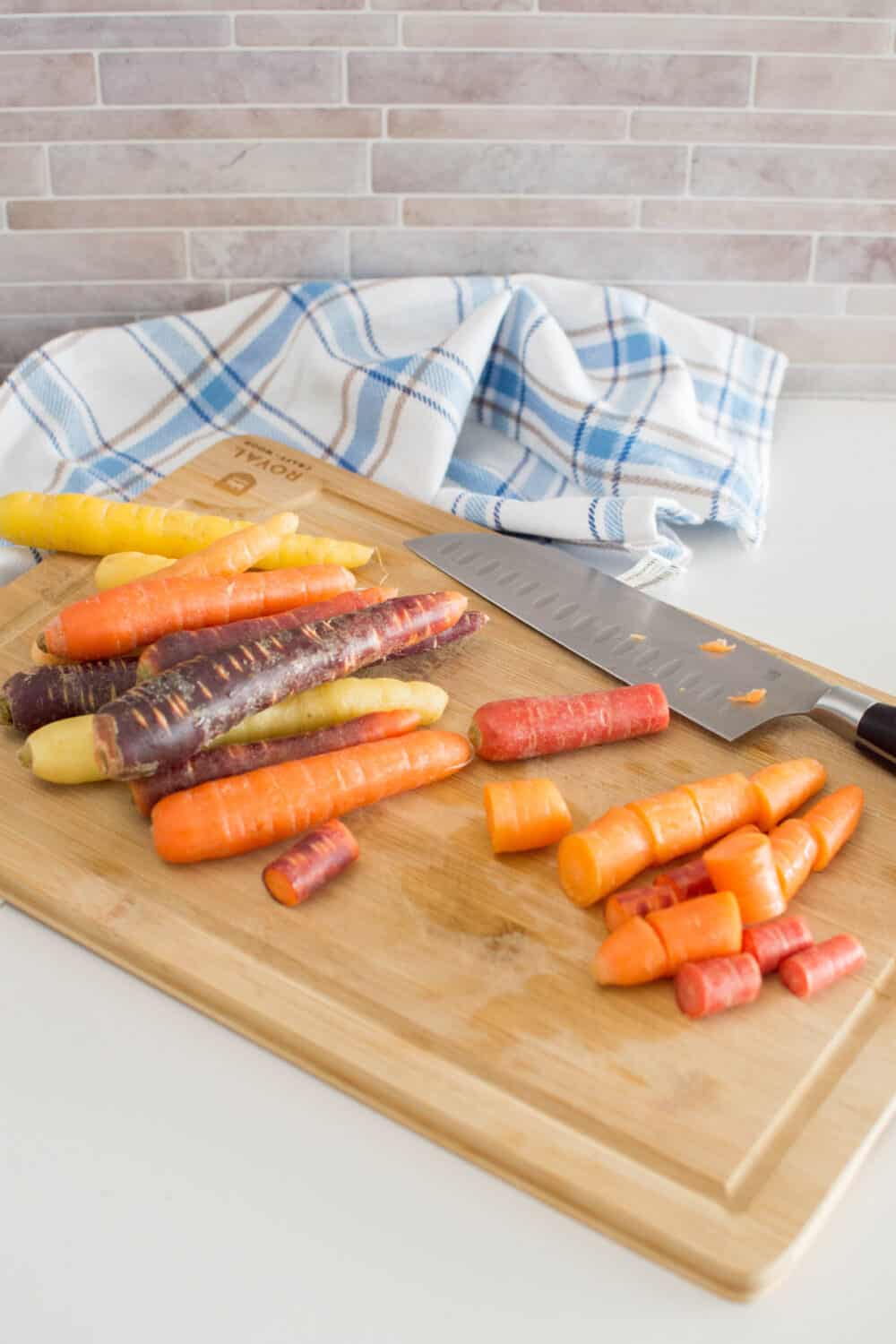 A mixture of different carrots being chopped on a wooden cutting board
