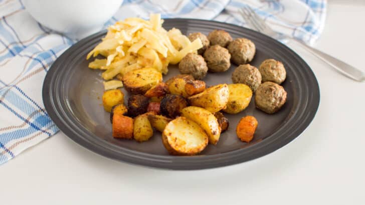 Roasted air fryer potatoes and carrots served on a grey plate with meatballs and pasta