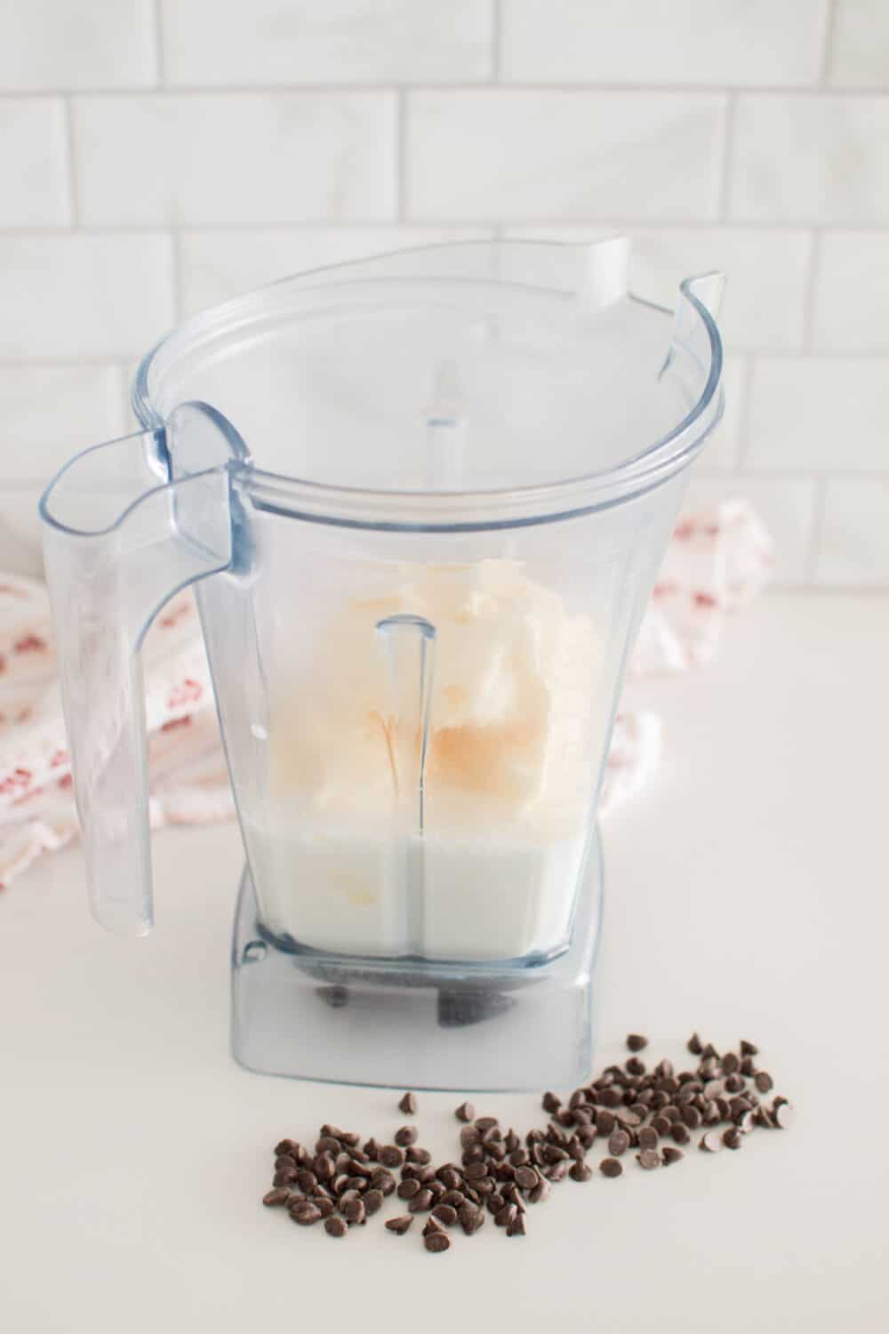 Mixing together milk and vanilla ice cream to a blender