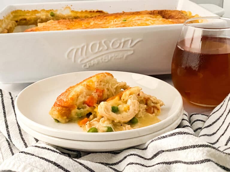 A slice of Cheddar Bay Biscuit Chicken Pot Pie served on a white plate, sitting on a striped tea towel