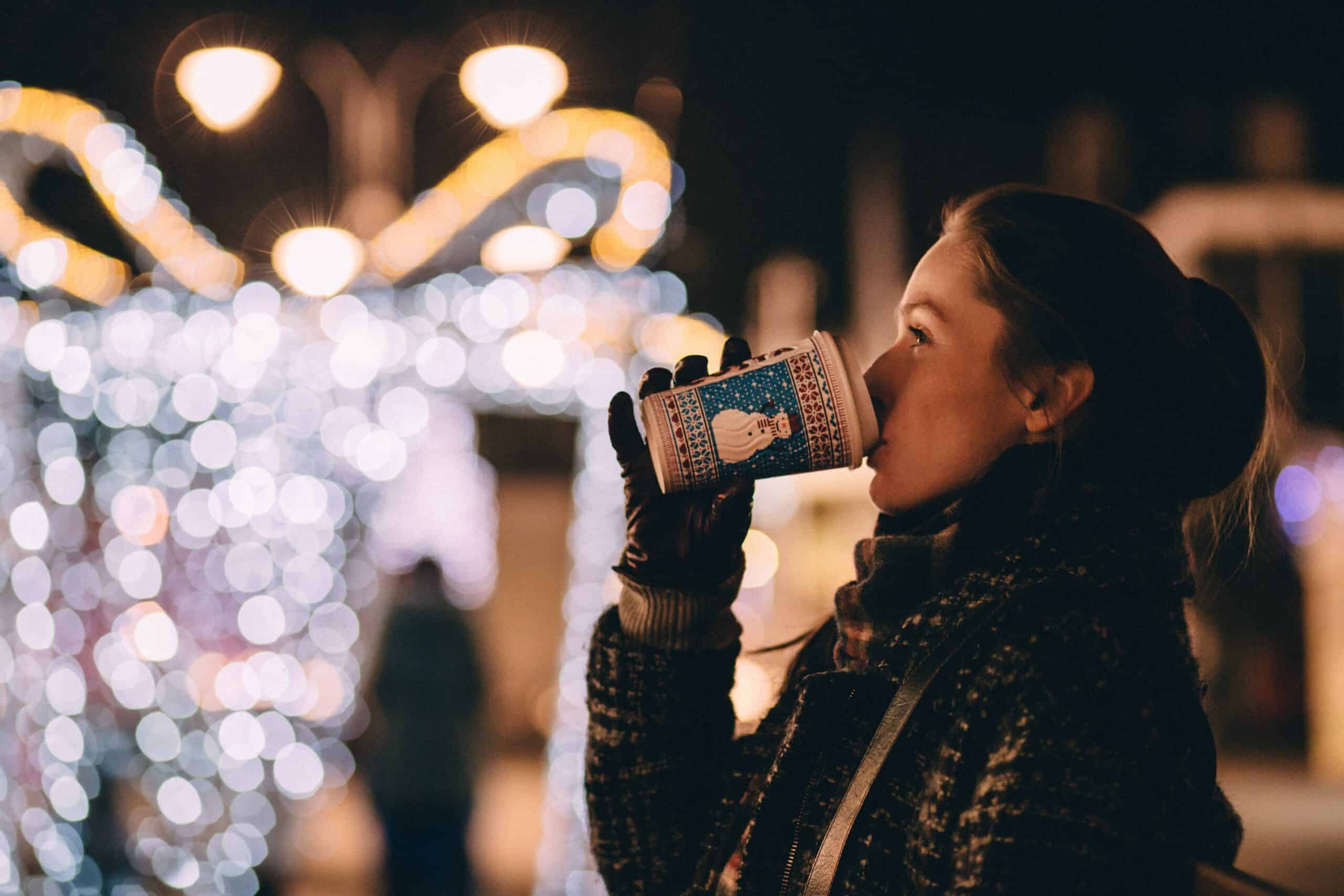Woman drinking out of a paper cup at a Christmas Market