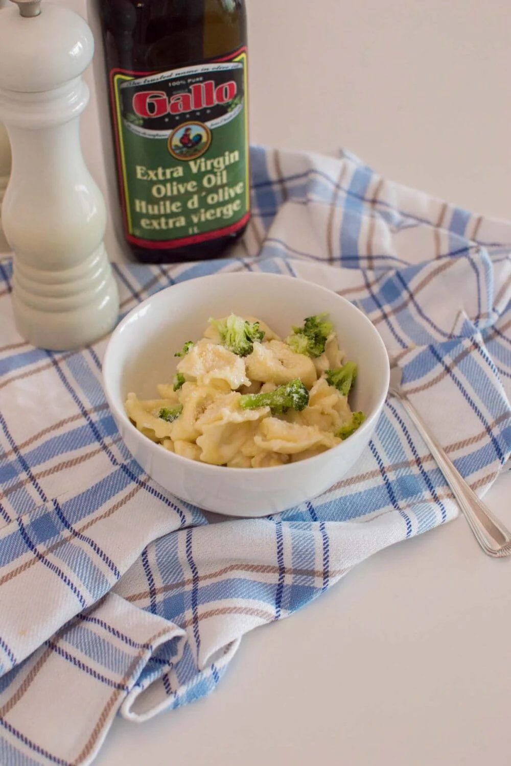A bowl of homemade alfredo tortellini with homemade sauce, sitting on a plaid napkin