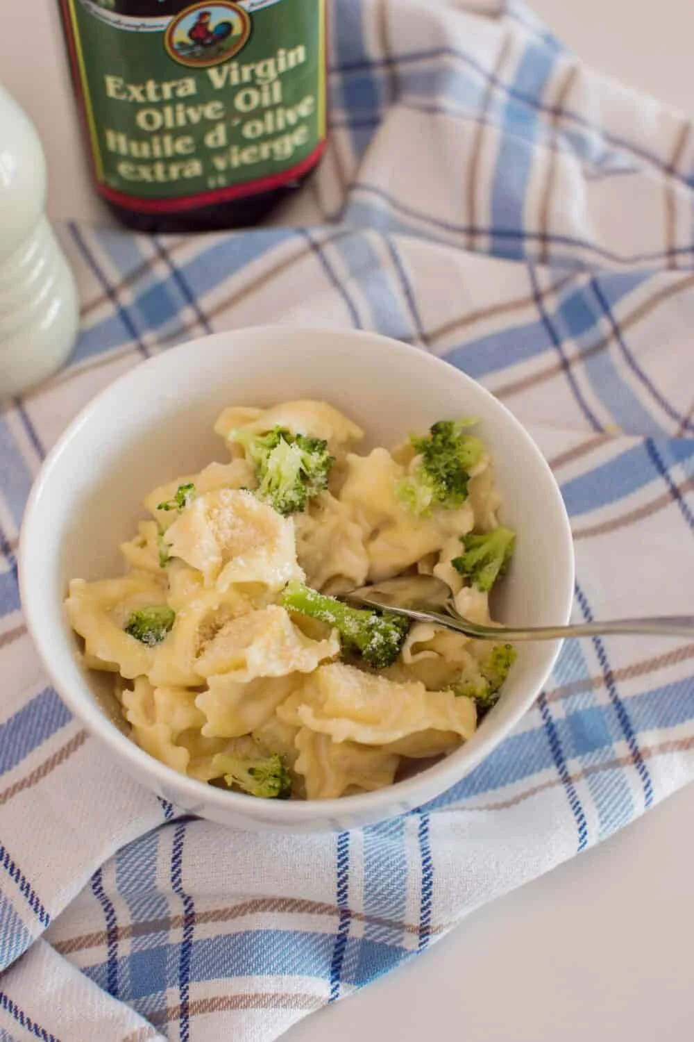 Bird's eye view of a bowl of homemade alfredo tortellini with homemade sauce, sitting on a plaid napkin