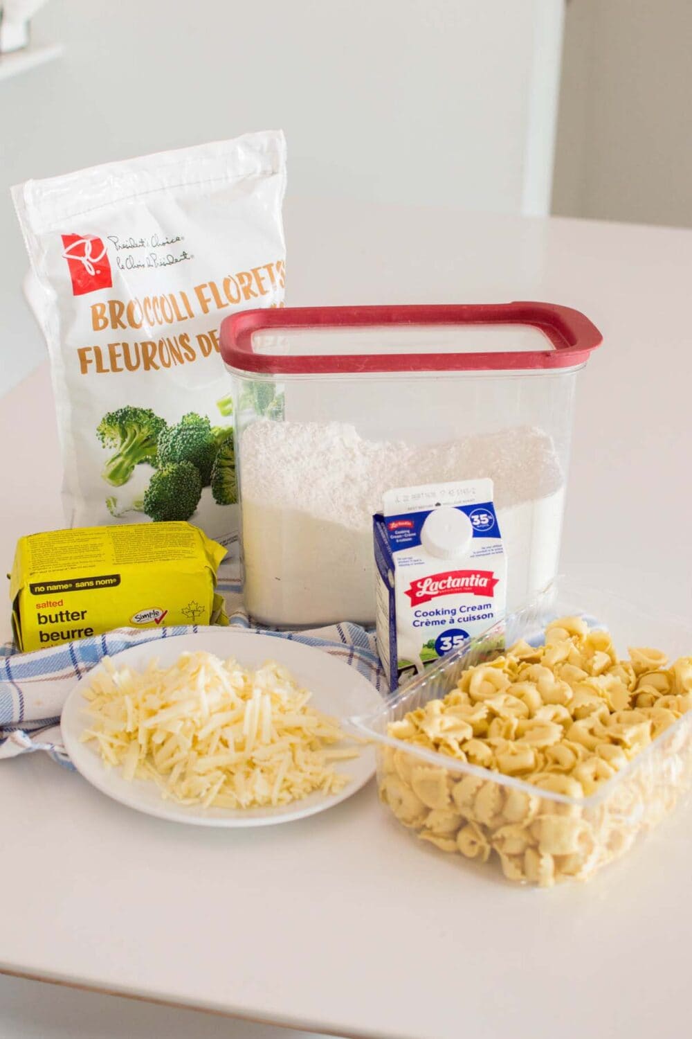 Ingredients required to make alfredo tortellini laid out on a white table