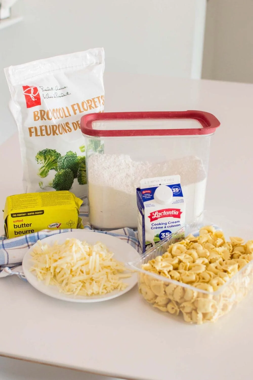 Ingredients required to make alfredo tortellini laid out on a white table