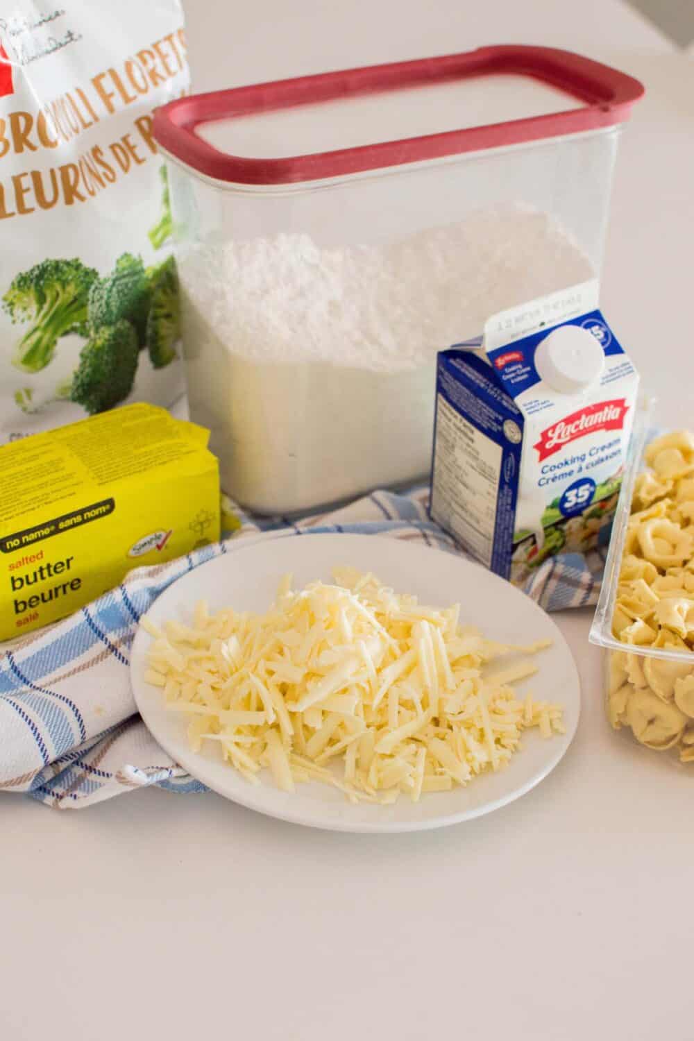 Close up photo of shredded cheese alongside other ingredients to make Alfredo Tortellini