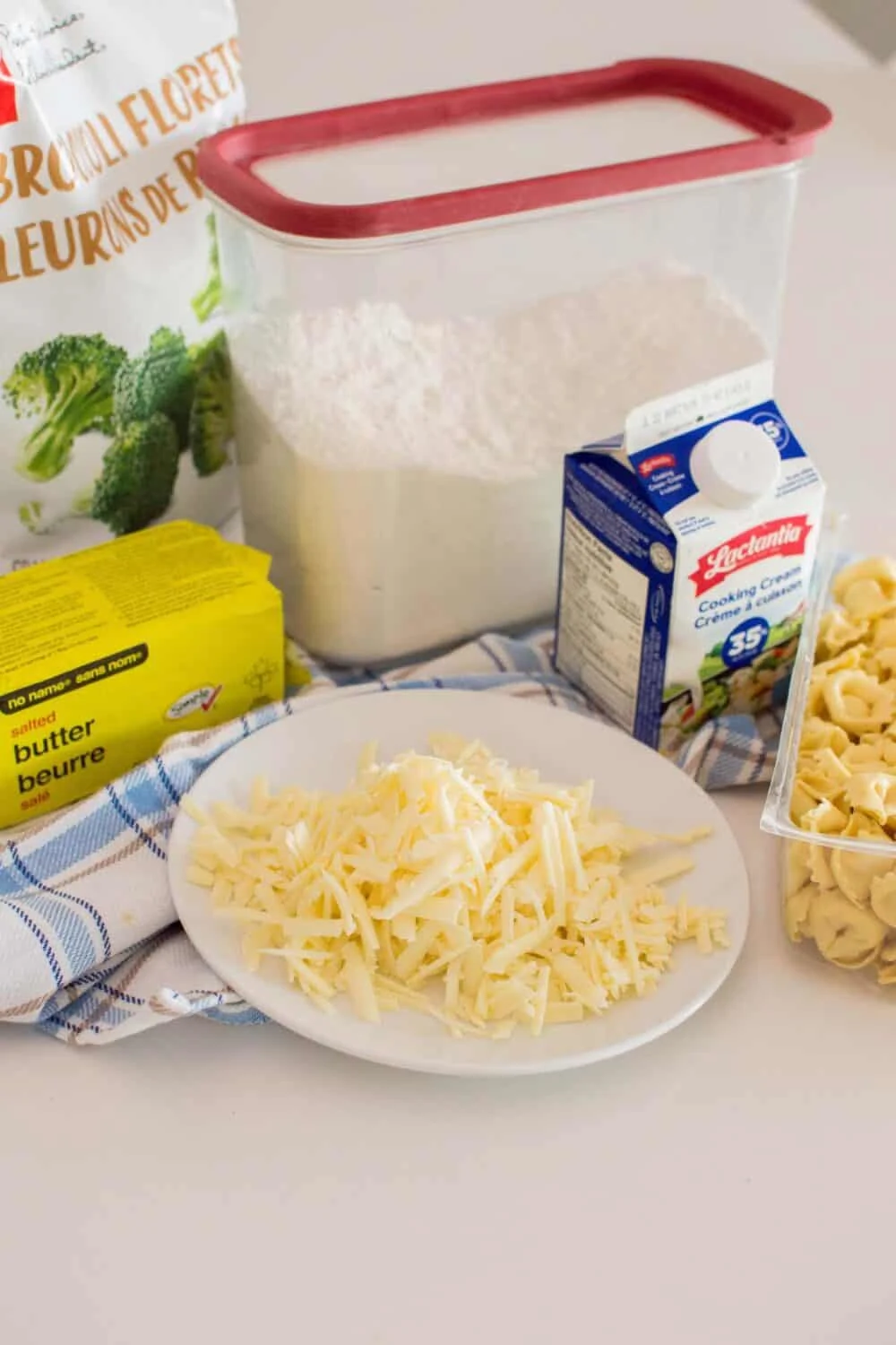 Close up photo of shredded cheese alongside other ingredients to make Alfredo Tortellini