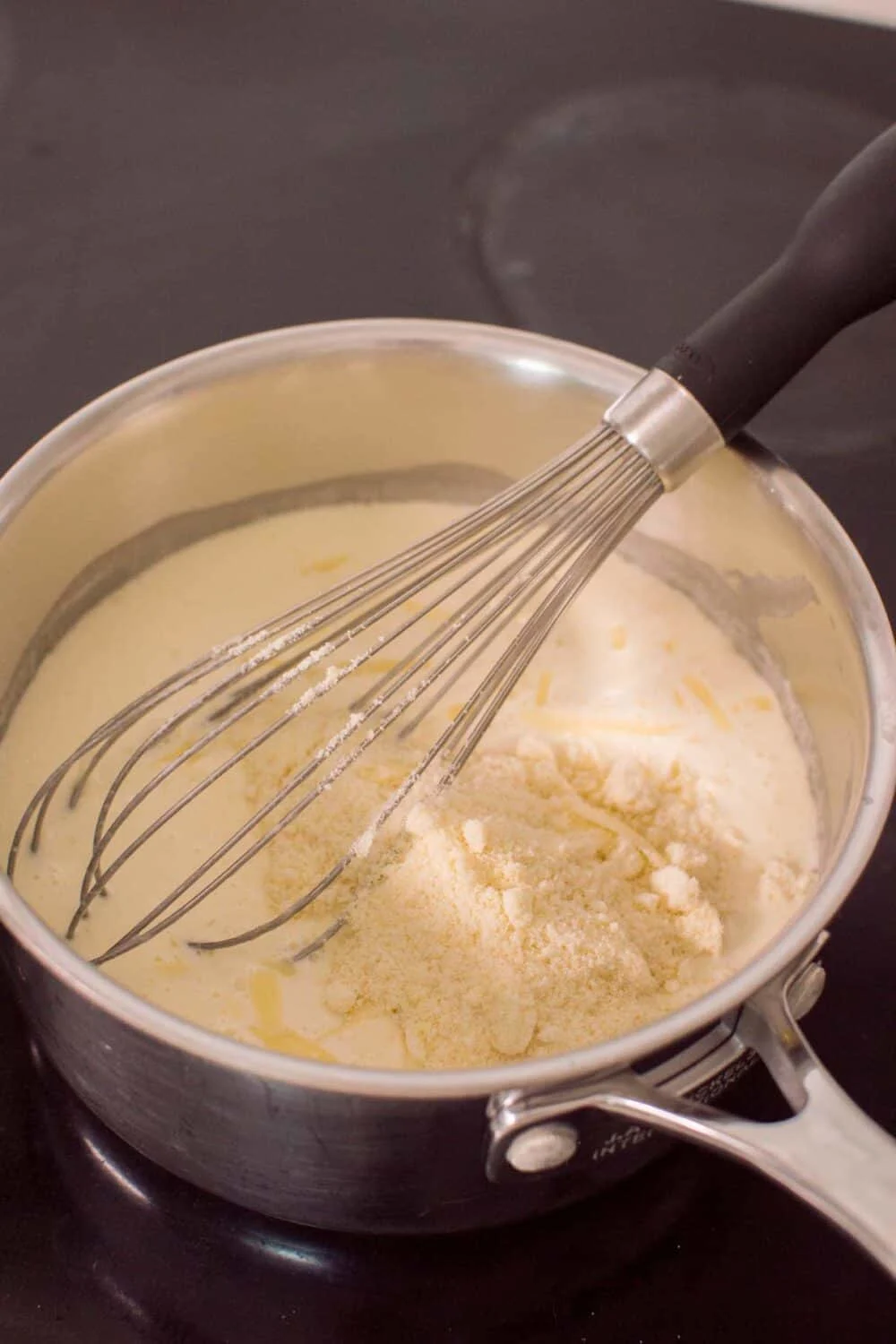 Adding parmesan cheese to our homemade alfredo sauce