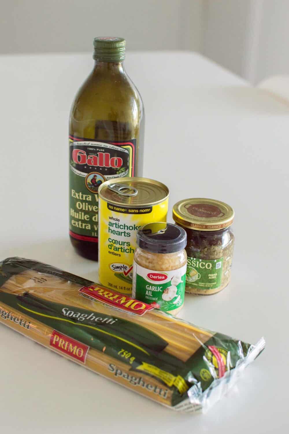 Ingredients gathered on a white kitchen table to make Artichoke Pesto Pasta