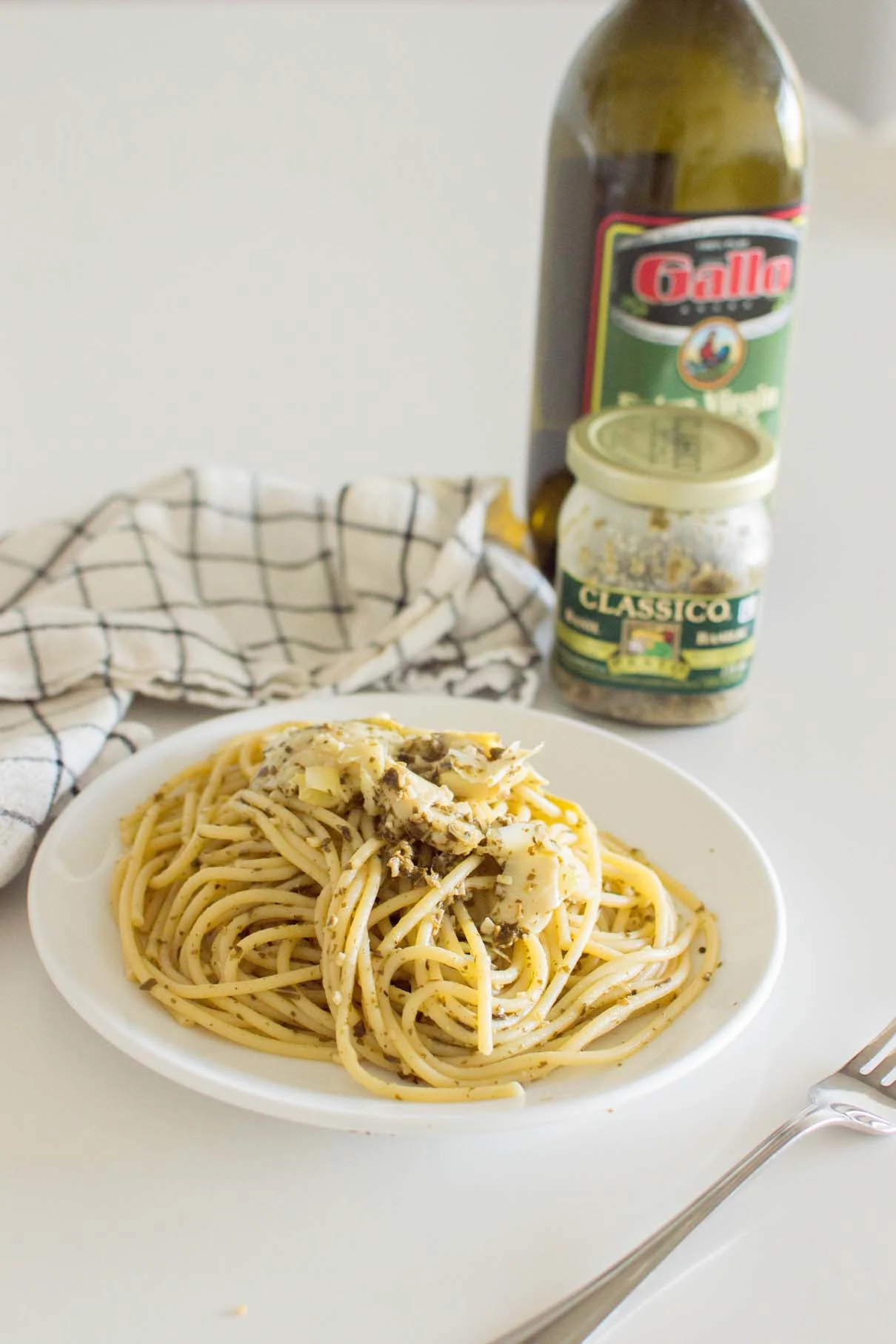 Artichoke Pesto Pasta served on a white plate with a napkin in the background