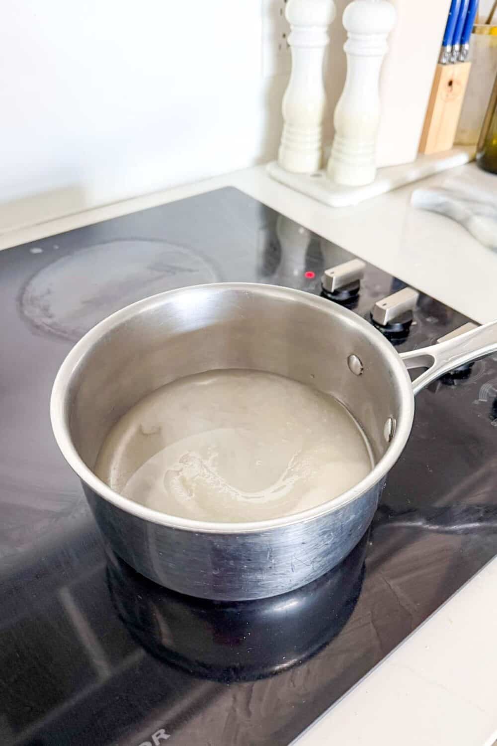 Boiling sugar and water in a small pot to make Jalapeno Peanut Brittle