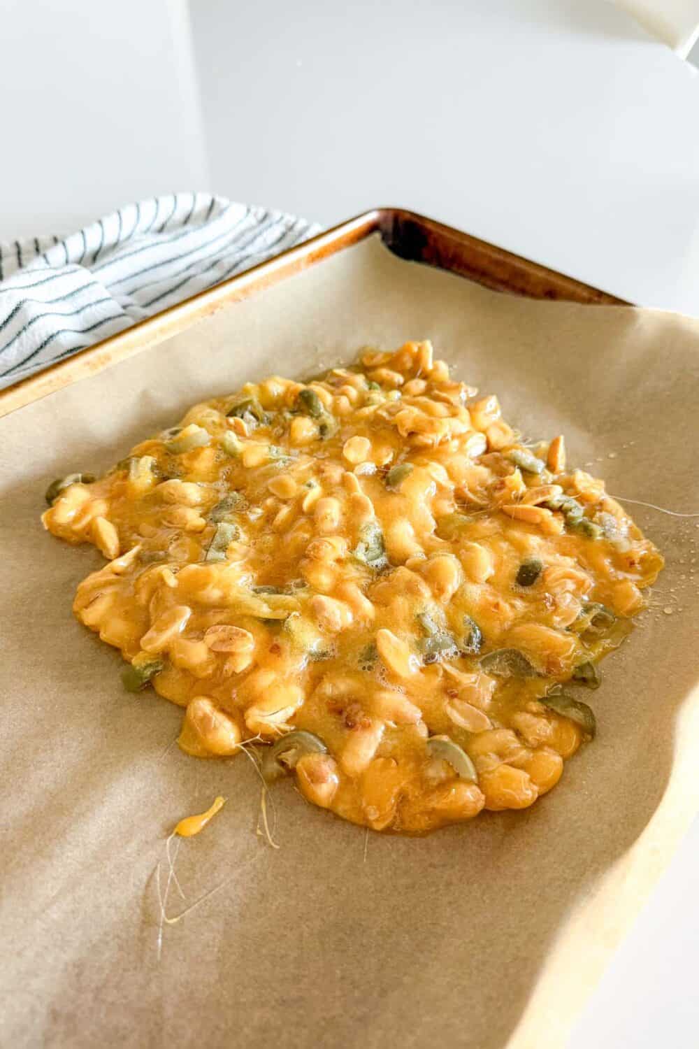 Jalapeno Peanut Brittle laid out on a parchment-lined baking sheet, ready to harden