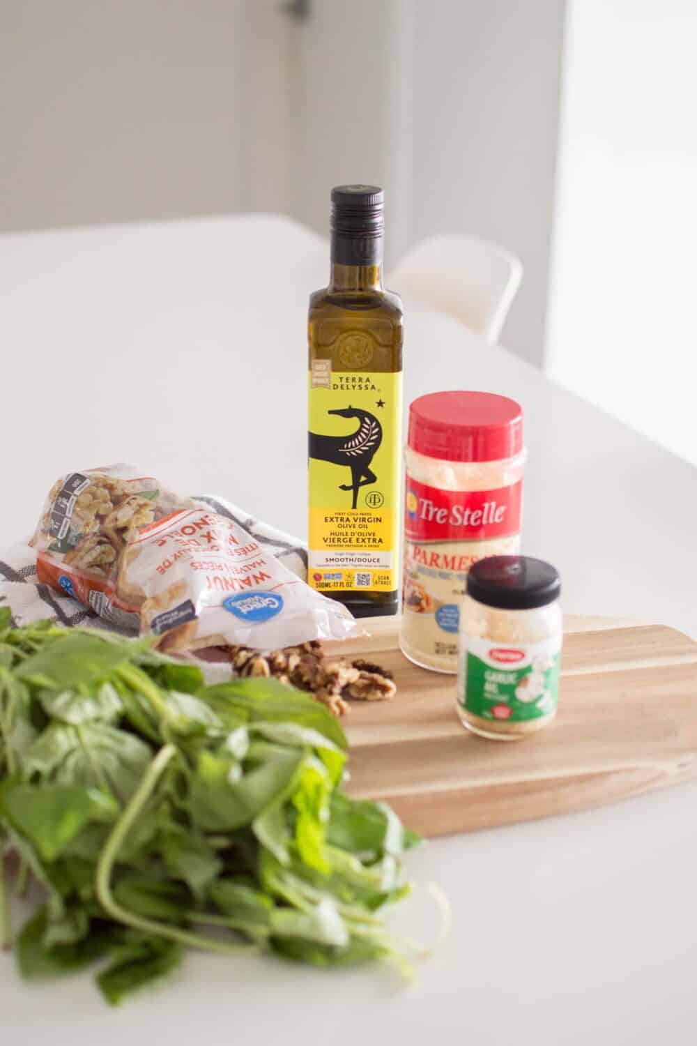 Ingredients for homemade pesto sauce displayed on a wooden cutting board