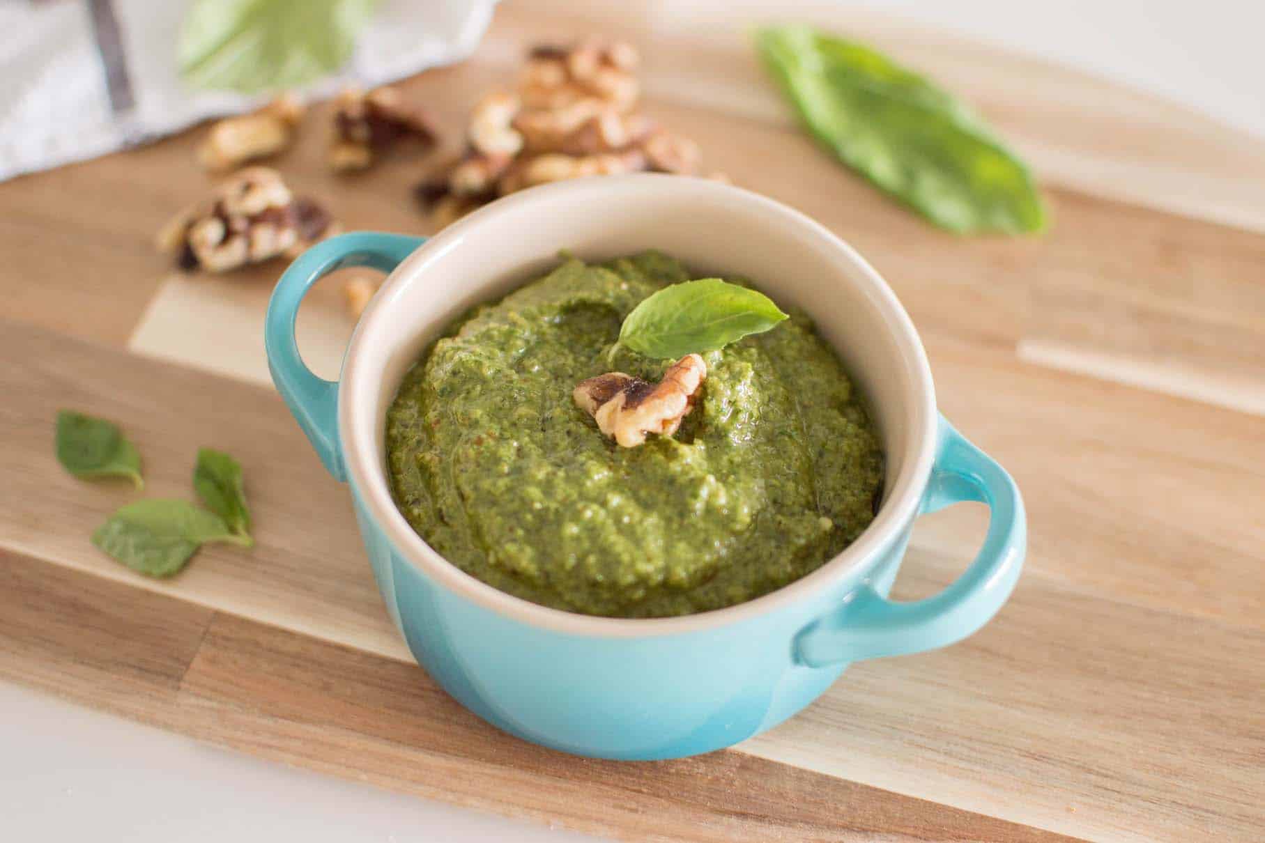 Bowl of fresh pesto sauce, served on a wood surface