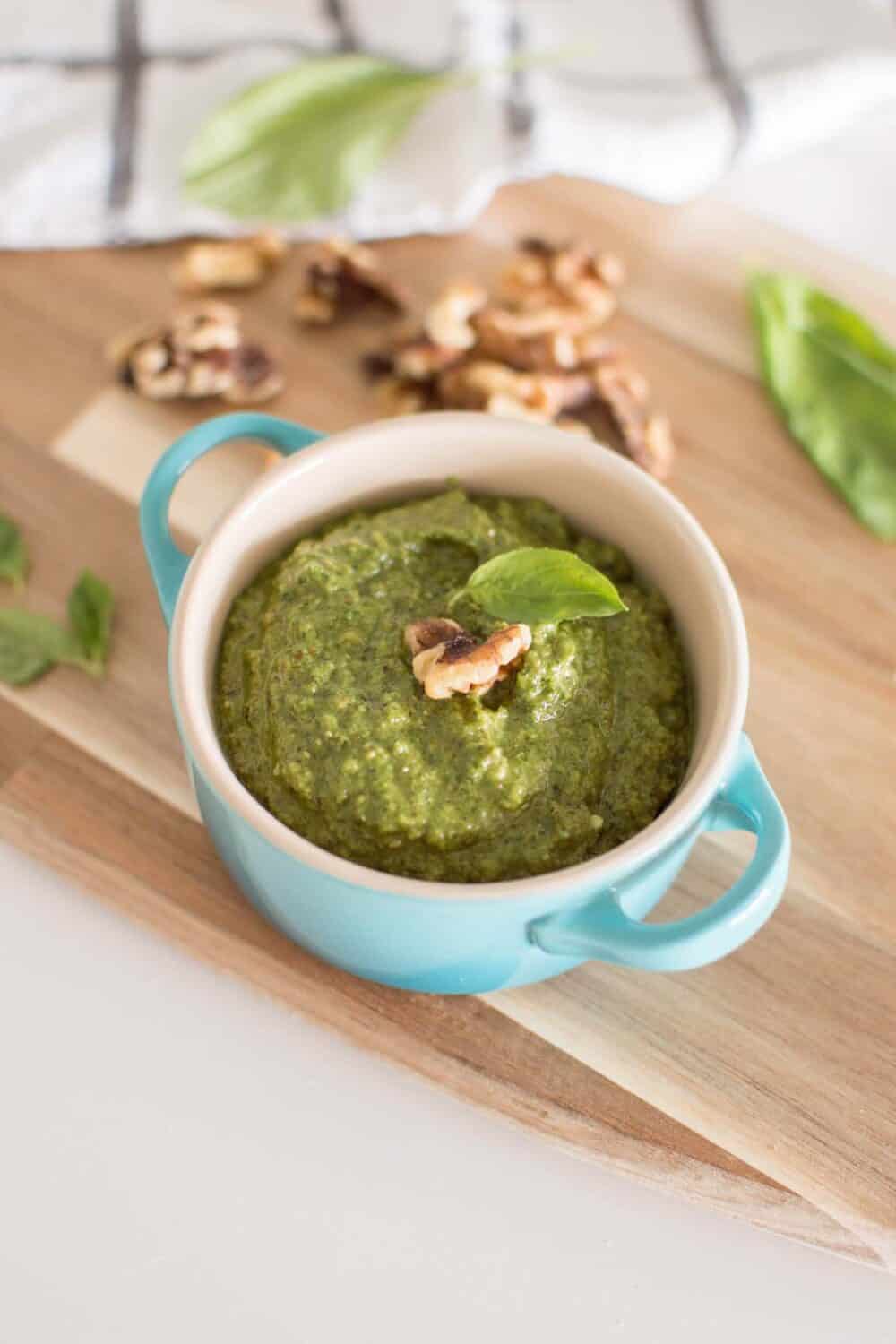 Bright green pesto in a white bowl, styled with olive oil drizzle