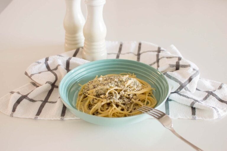 Alfredo Pesto Pasta served in a green dish on a tea towel