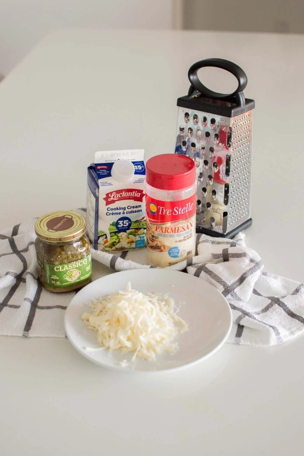 Ingredients required to make Alfredo Pesto Pasta on a white towel