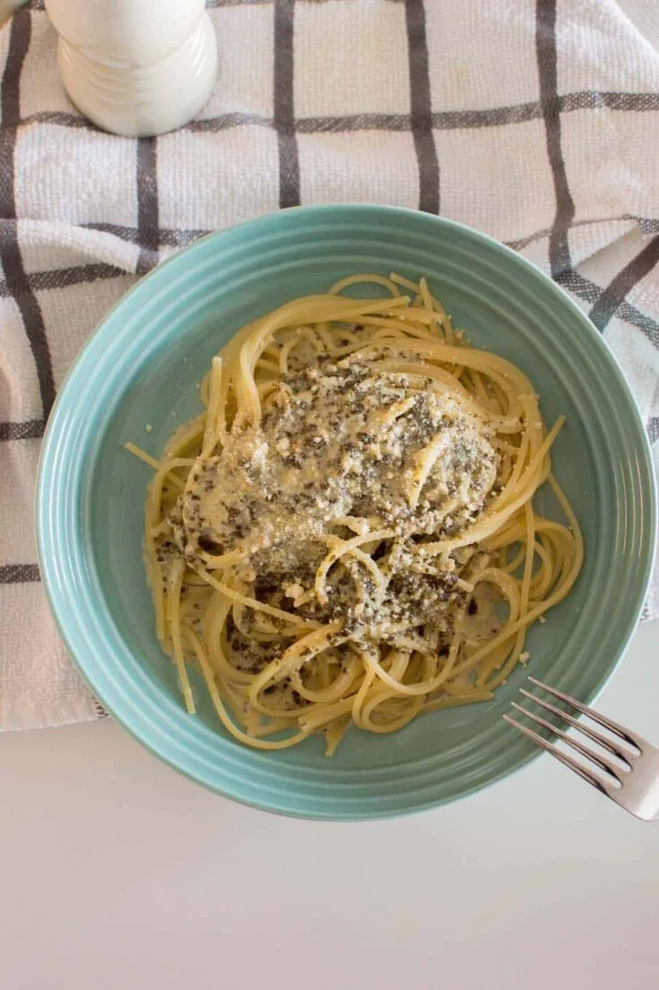 Bird's eye view of Alfredo Pesto Pasta served in a green dish on a tea towel
