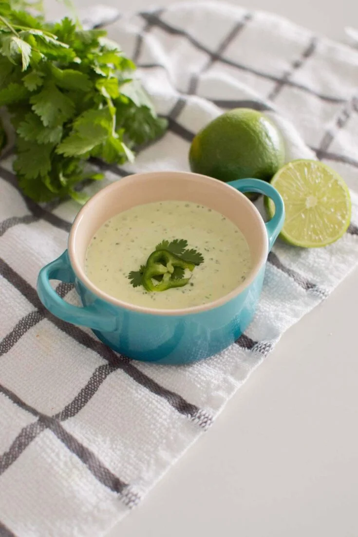 Easy Jalapeno Aioli Recipe served in a blue serving dish, surrounded by limes and fresh cilantro