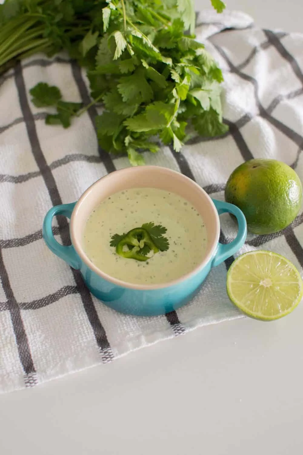 Easy Jalapeno Aioli Recipe served in a blue serving dish, surrounded by limes and fresh cilantro