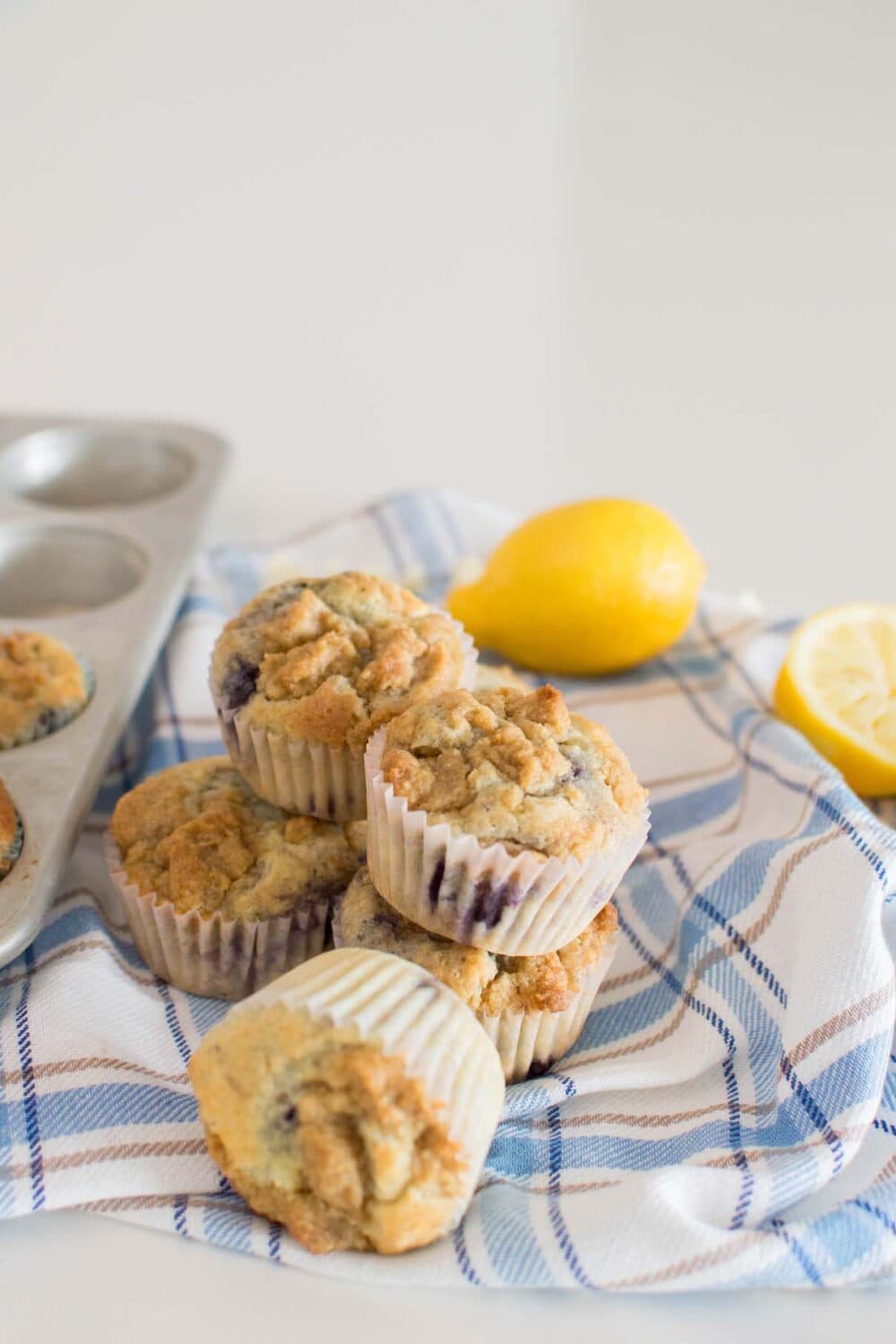 Lemon Blueberry White Chocolate Muffins stacked and on a plaid tea towel