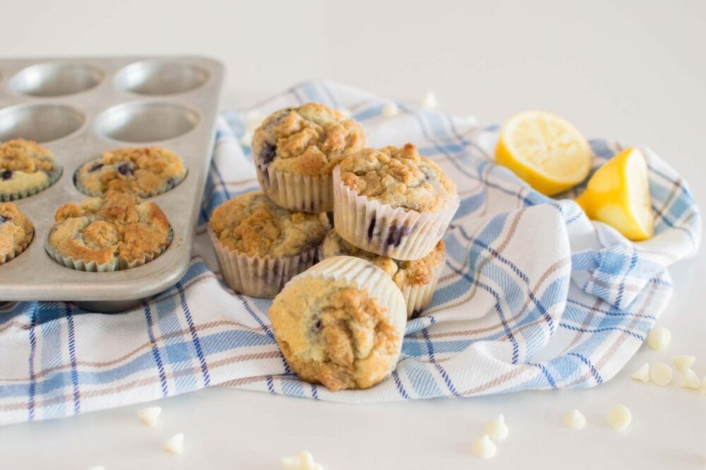 Lemon Blueberry White Chocolate Muffins stacked and on a plaid tea towel