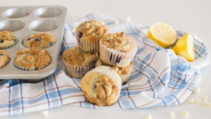 Lemon Blueberry White Chocolate Muffins stacked and on a plaid tea towel