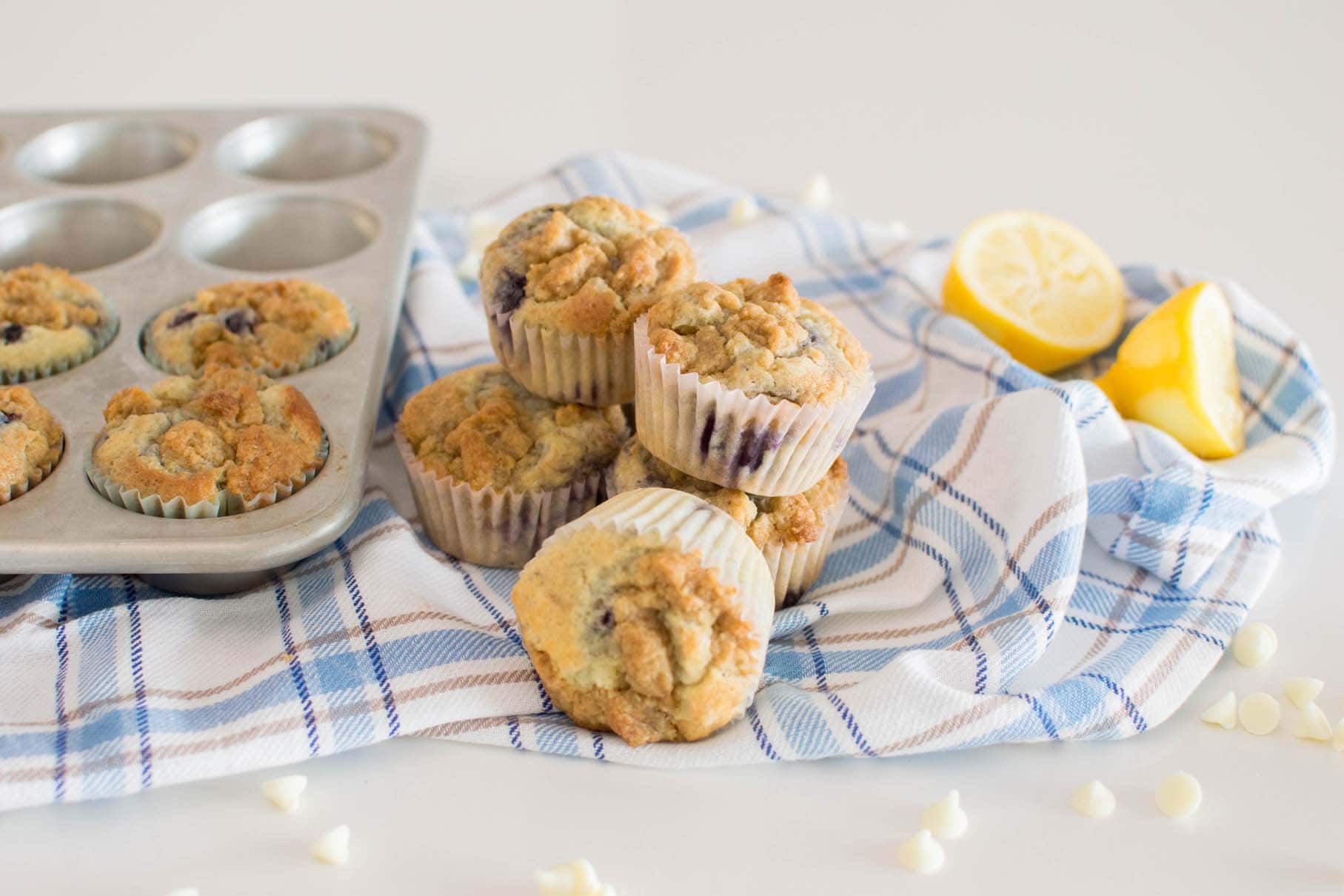 Lemon Blueberry White Chocolate Muffins stacked and on a plaid tea towel