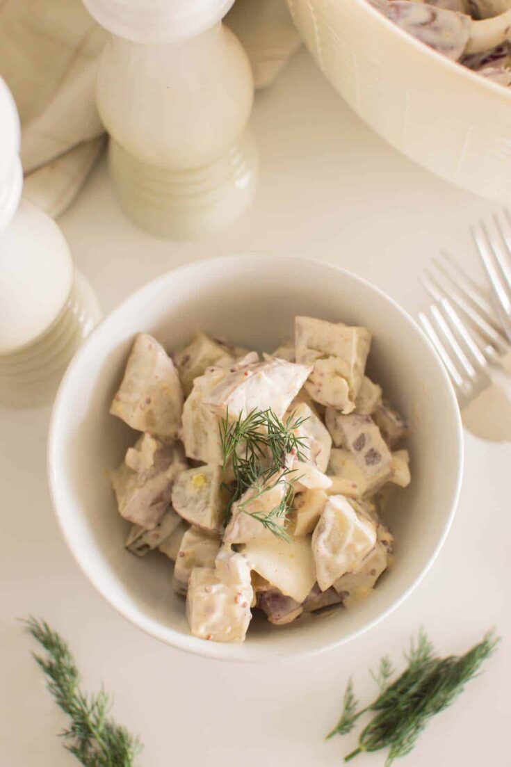 Creamy potato salad with dill pickles and bacon in serving bowl