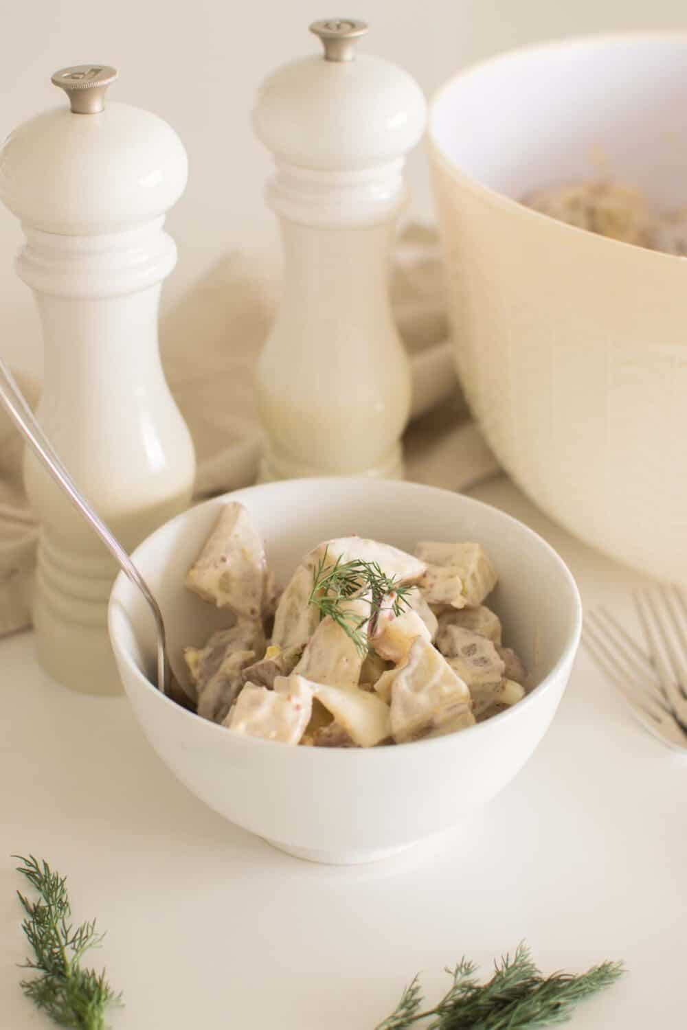 Creamy potato salad with dill pickles and bacon in serving bowl