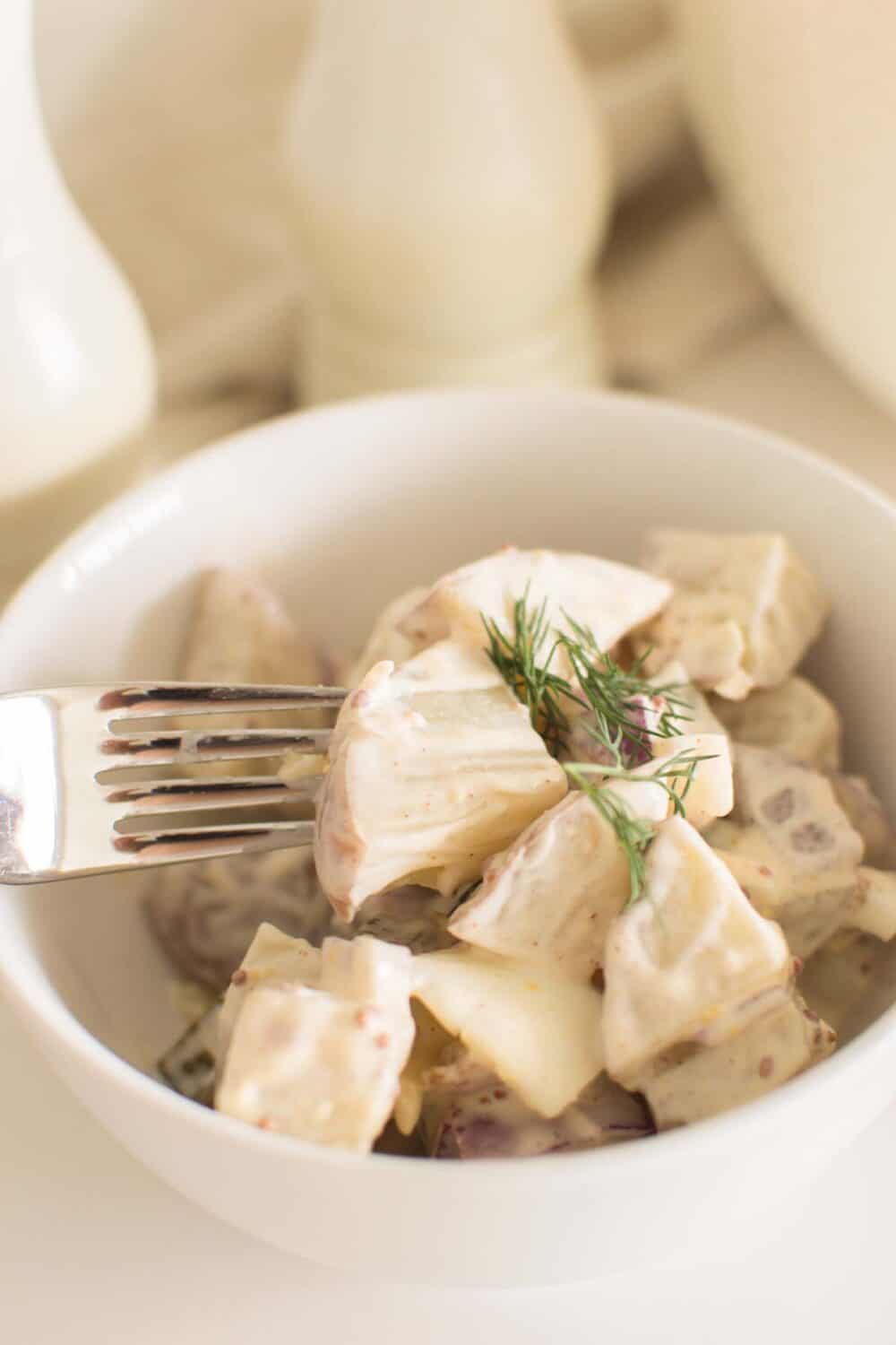 Creamy potato salad with dill pickles and bacon in serving bowl