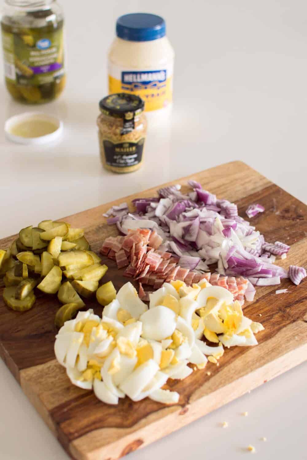 Chopped potatoes, eggs, bacon, and pickles ready to mix for potato salad