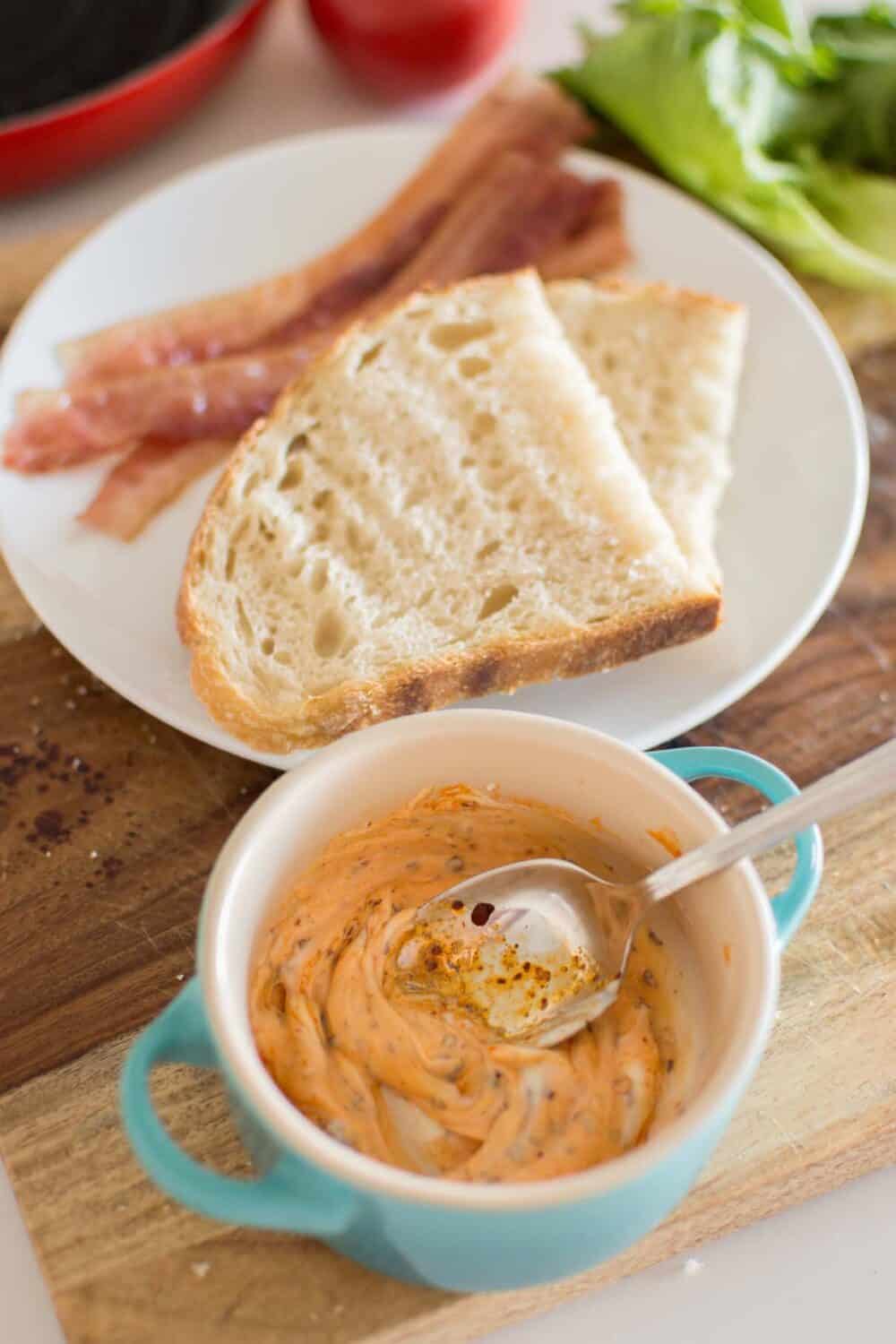 Mayo mixture being spread on toasted bread for BLT sandwich