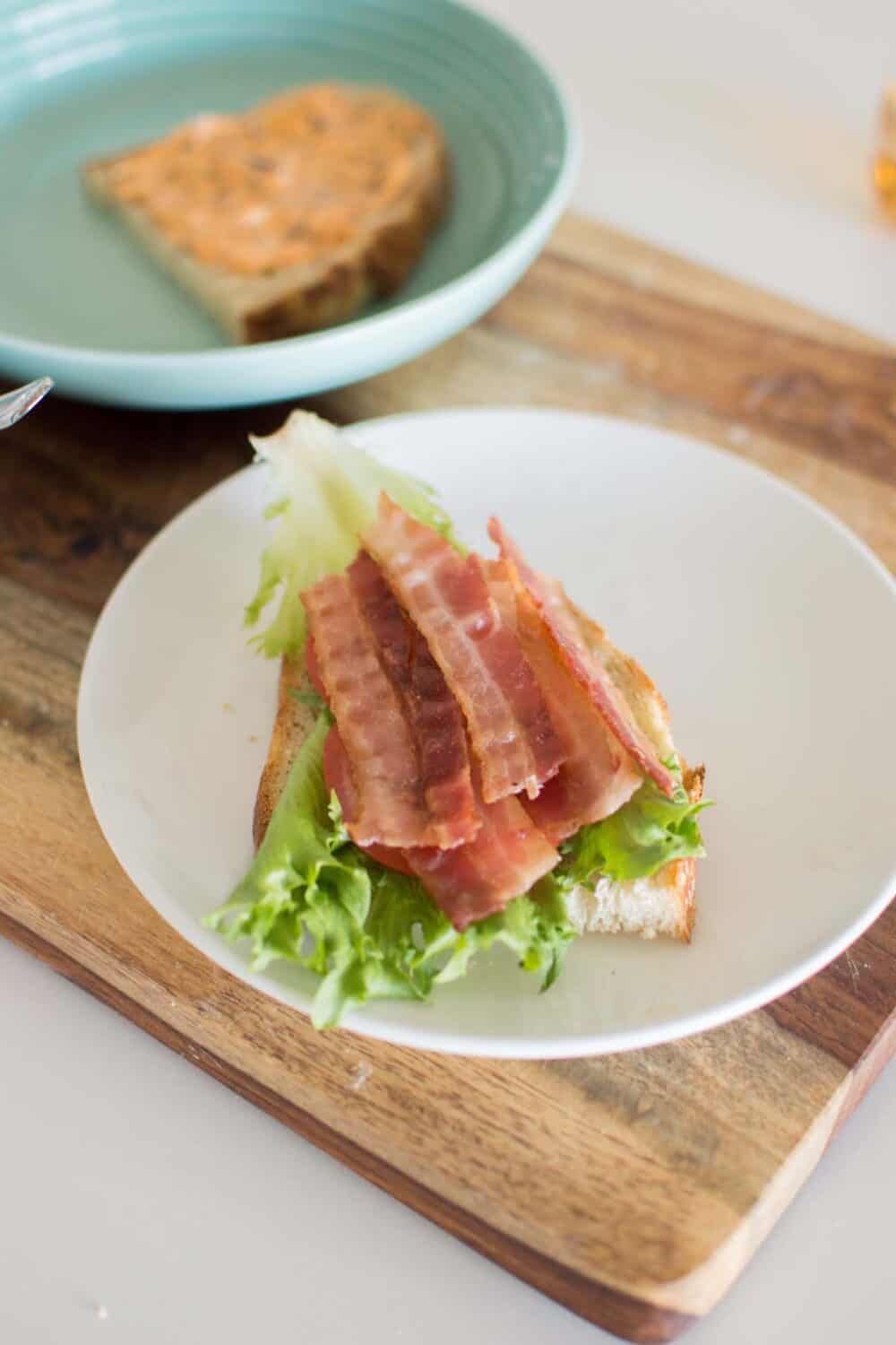 Hot honey BLT sandwich assembled and cut in half on a plate
