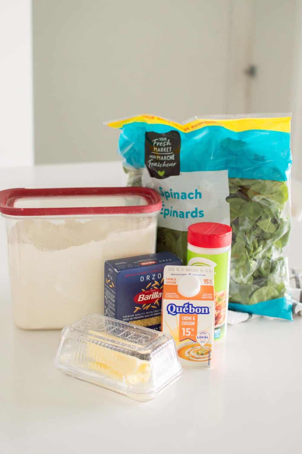 Ingredients for creamy spinach parmesan orzo arranged on a countertop