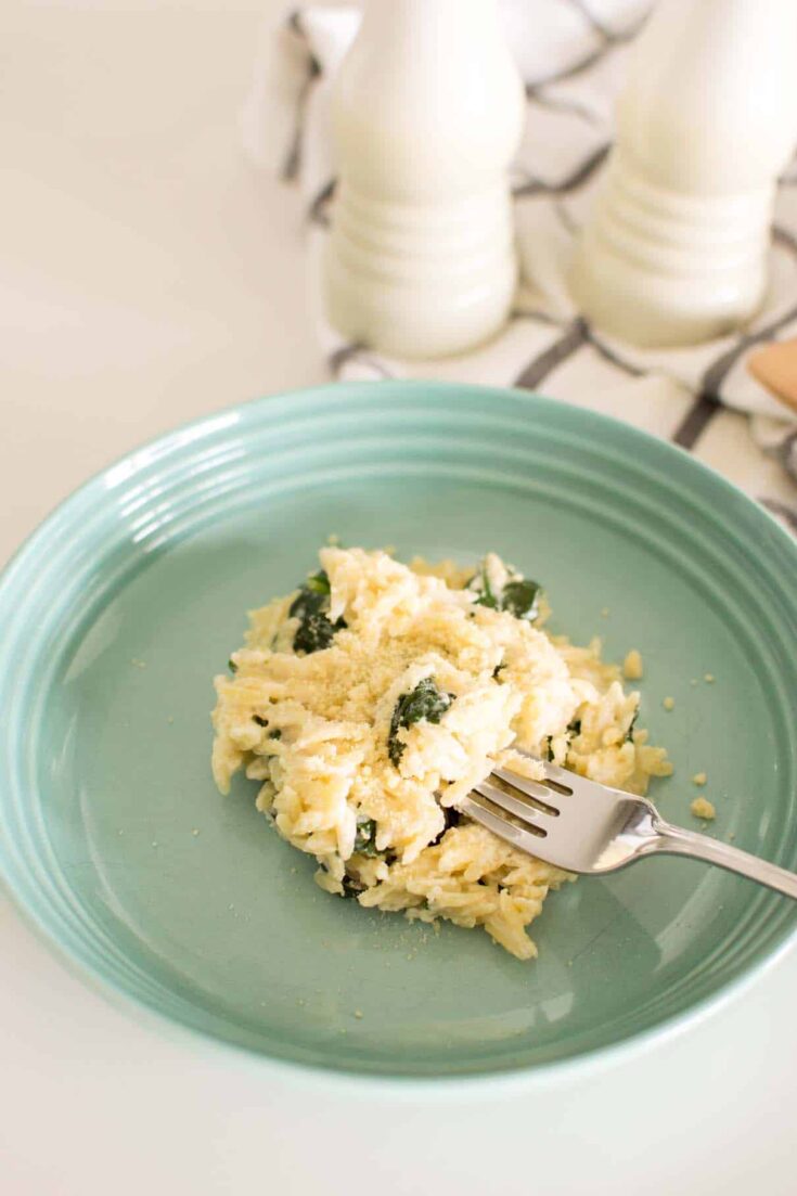 Creamy parmesan orzo with fresh spinach on a serving plate